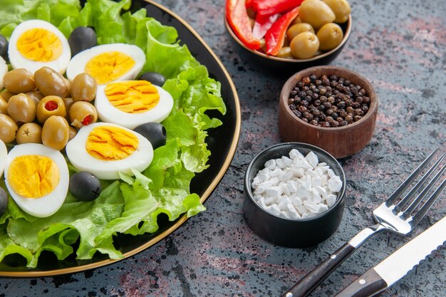 Eiersalat aus der Nähe besteht aus grünem Salat und Oliven auf hellem Hintergrund