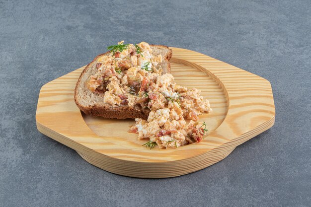 Eiersalat und Brot auf Holzplatte.