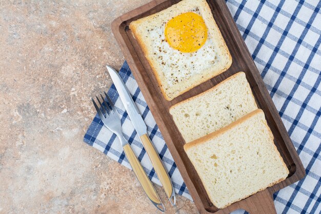 Eiertoast mit Gewürzen auf Holzbrett mit Besteck