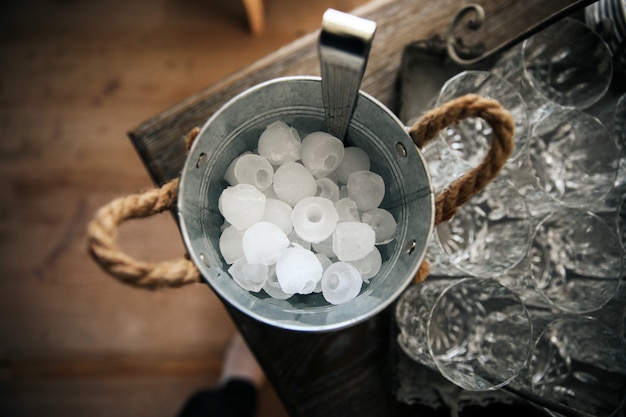 Eimer mit Eis steht auf dem Tisch neben den Gläsern