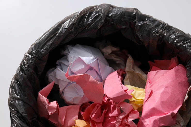 Kostenlose Foto eimer mit müllbeutel und papier auf weißem hintergrund in der nähe