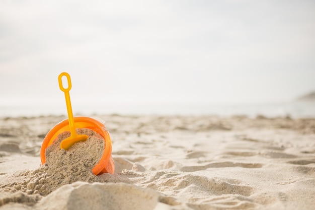 Eimer mit Sand und einem Spaten auf Strand