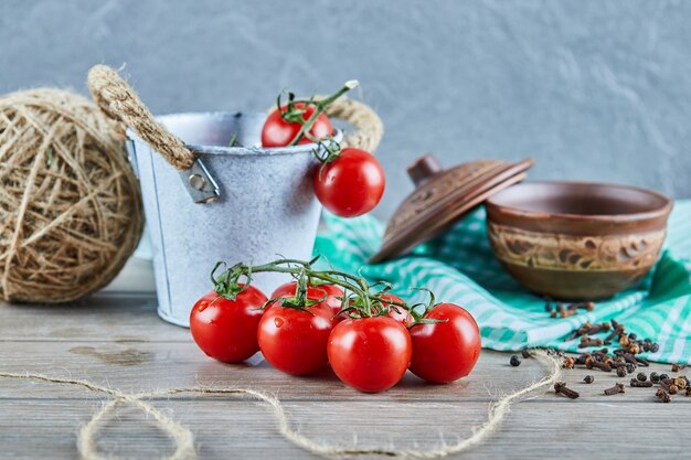 Eimer mit Tomaten und Nelken auf Holztisch mit leerer Schüssel