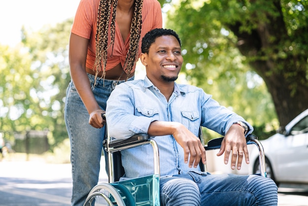 Kostenloses Foto ein afroamerikaner im rollstuhl, der mit seiner freundin einen spaziergang im freien macht