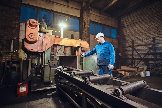 Ein Arbeiter kontrolliert einen Prozess des Schienenschneidens in einer geschäftigen Metallfabrik.