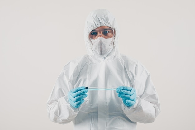 Ein Arzt in medizinischen Handschuhen und Schutzanzug stehend und hält Medizin in hellem Hintergrund. Coronavirus