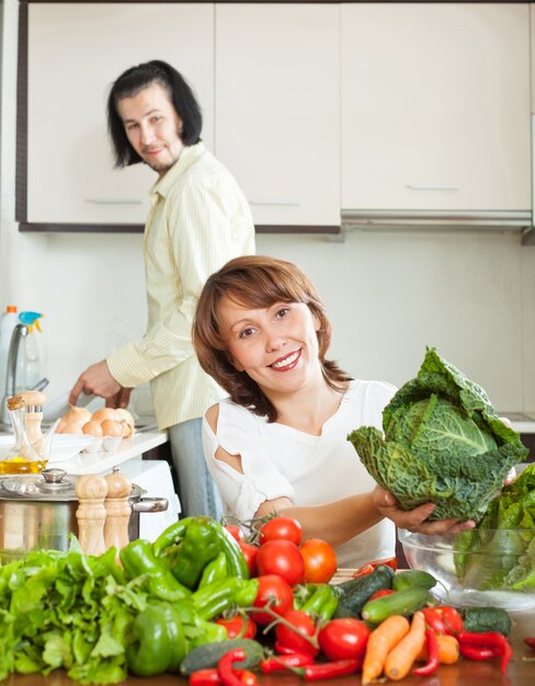 Ein attraktiver Mann und eine Frau mit Gemüse in der Küche