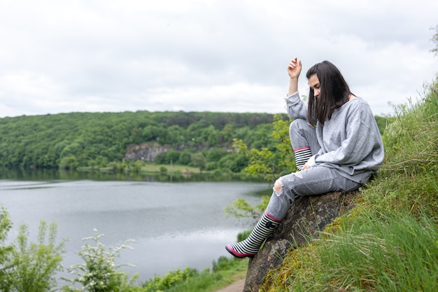 Ein attraktives Mädchen kletterte bei einem Spaziergang auf eine Klippe in einer bergigen Gegend und genießt die Landschaft.