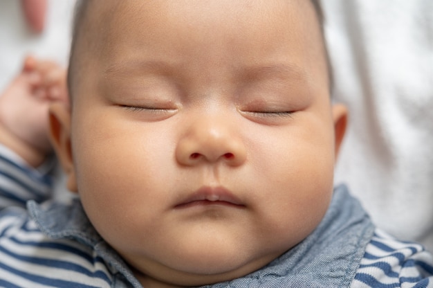 Ein Baby in einem gestreiften Hemd schläft im Bett.