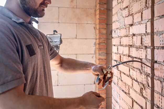 Ein Bauelektriker schneidet bei einer Reparatur ein Spannungskabel durch