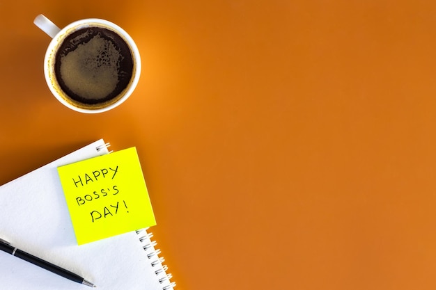 Ein Becher Kaffeebuch und eine Aufschrift Glücklicher Cheftag auf einer Erinnerungspapierplatte