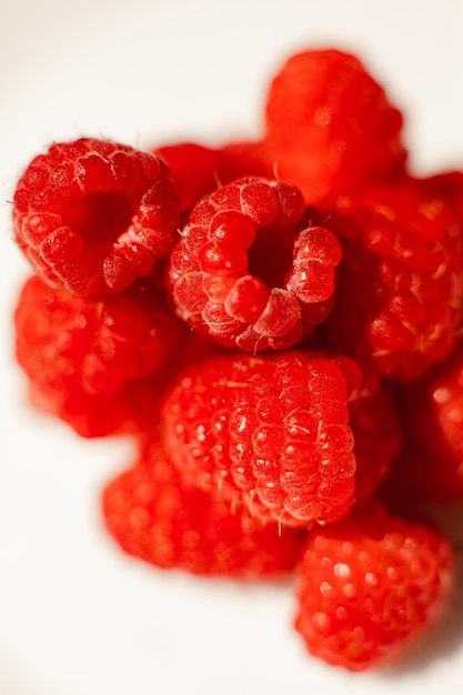 Ein Bild von ein paar frischen rosa Himbeeren liegt auf einem weißen Hintergrund. Hintergrund und Bild für Postkarte.