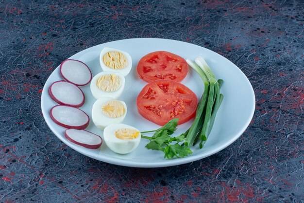 Ein blauer Teller mit hartgekochten Eiern mit Gemüse
