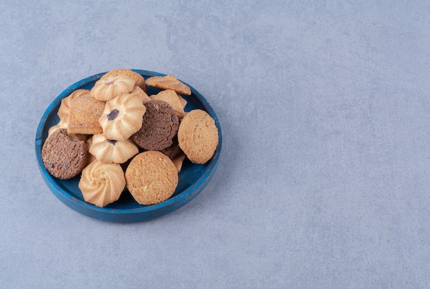 Ein blaues Holzbrett mit süßen runden leckeren Keksen auf Sackleinen.