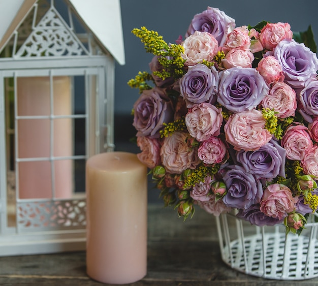 Ein Bouquet von roten und violetten Rosen mit Blättern mit rosa Kerzen herum