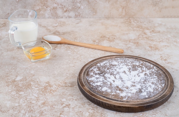 Ein brauner Teller Mehl und ein Holzlöffel Zucker