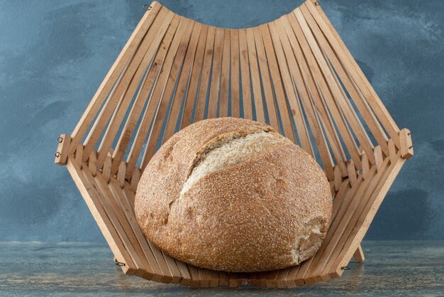 Ein Brötchen frisches Schwarzbrot auf Holzkorb