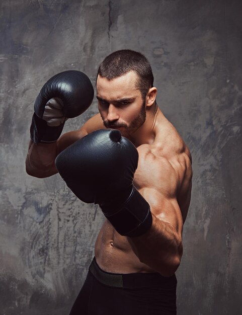 Ein brutaler muskulöser Boxer mit Boxhandschuhen, der an der Schlagtechnik arbeitet.