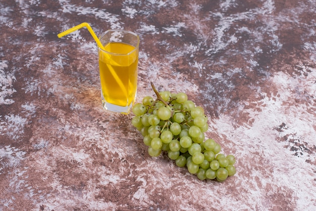 Ein Bündel grüner Trauben und ein Glas Saft