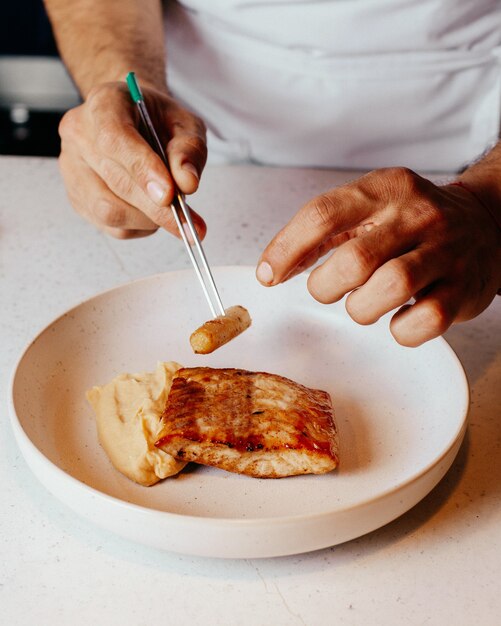 Ein Draufsichtkoch, der Mahlzeit innerhalb der weißen Platte und in der Küche Essen Mahlzeit Abendessen Küche zubereitet