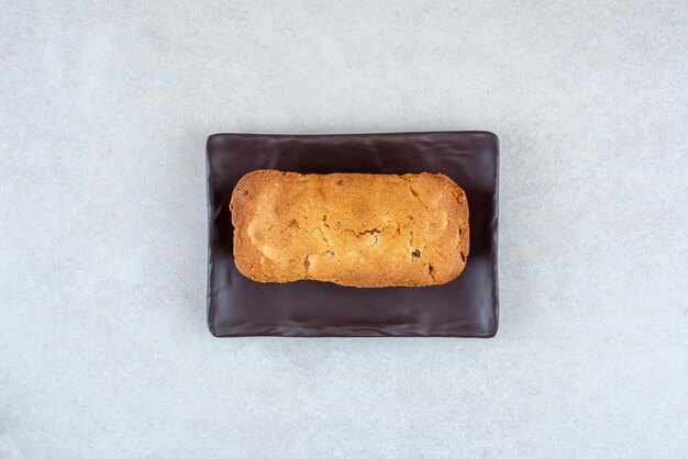 Ein dunkler Teller mit köstlichem frischem Kuchen auf weißem Tisch.