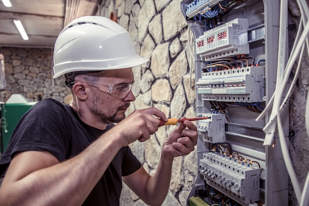 Kostenloses Foto ein elektriker arbeitet in einer schalttafel mit einem elektrischen verbindungskabel