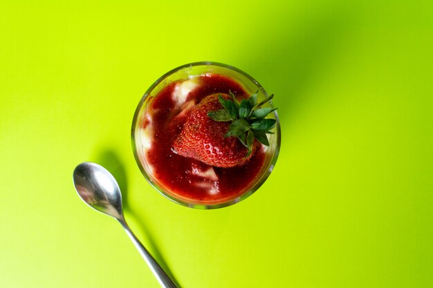 Ein Erdbeerdessert der Draufsicht mit frischen roten Erdbeeren innerhalb des kleinen Glases, das auf Grün lecker ist