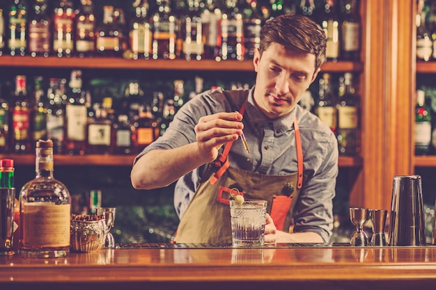 Ein erfahrener Barmann macht einen Cocktail im Nachtclub oder in der Bar.