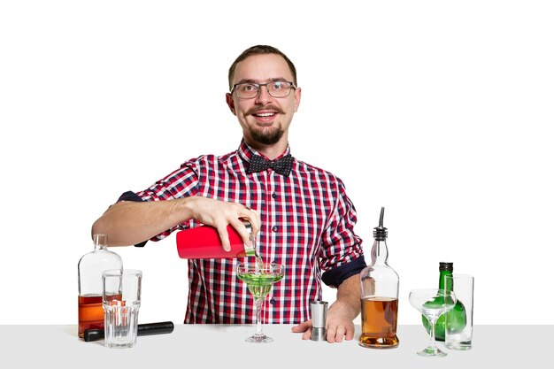 Ein erfahrener männlicher Barmann macht Cocktail isoliert auf weißer Wand. Internationaler Barmann Tag, Bar, Alkohol, Restaurant, Party, Pub, Nachtleben, Cocktail, Nachtclub-Konzept