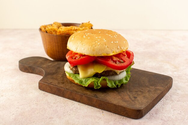 Ein Fleischburger der Vorderansicht mit grünem Gemüsekäse-Salat und Hühnerflügeln auf dem Holztisch