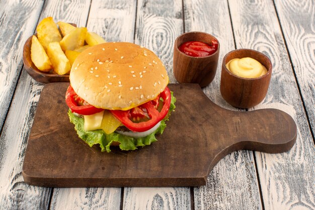 Ein Fleischburger von oben mit Käse und Kartoffeln mit grünem Salat und Dips