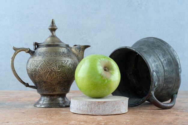 Ein frischer Apfel mit einer alten Tasse auf Marmortisch.