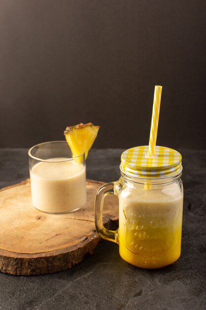 Ein frischer Cocktail leckeres kühlendes Getränk der Vorderansicht innerhalb der Dose mit Strohhalm nahe Holzschreibtisch auf dem dunklen Hintergrund trinken Sommersaft