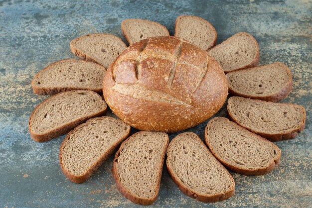 Kostenloses Foto ein frisches braunes brötchen mit scheiben auf marmorhintergrund