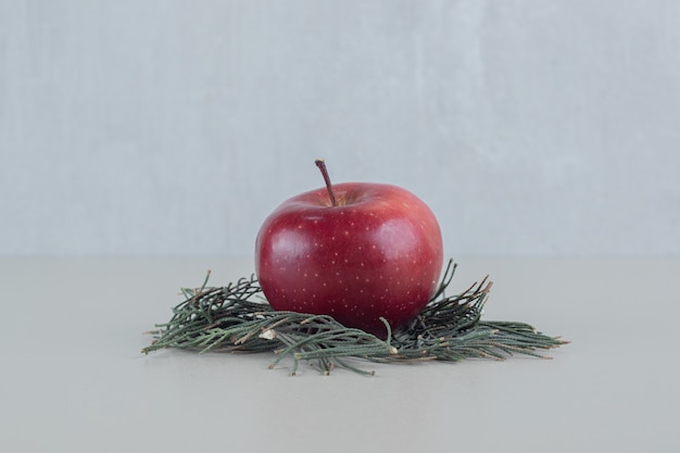 Ein ganzer roter frischer Apfel auf grauem Hintergrund.