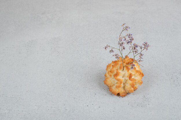 Ein ganzer süßer Cupcake mit verwelkter Blume.