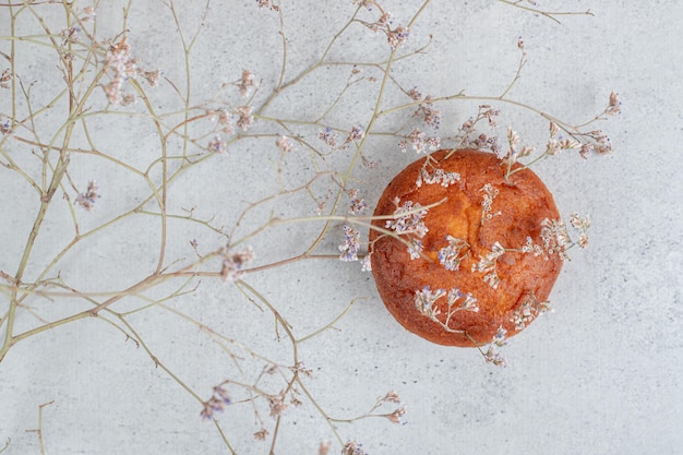 Kostenloses Foto ein ganzer süßer cupcake mit verwelkter blume.