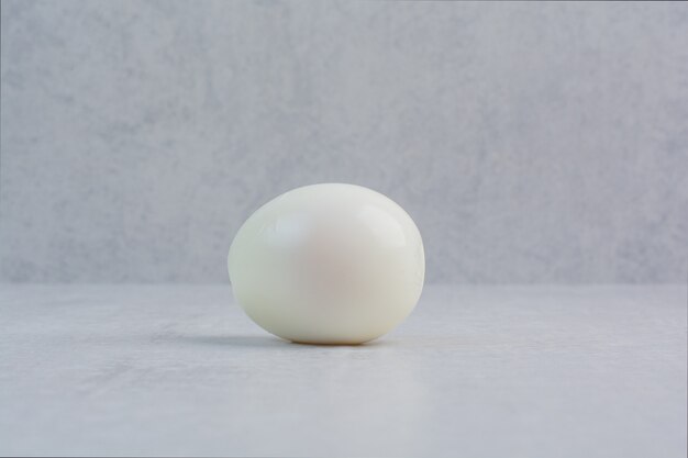 Ein ganzes gekochtes Ei auf grauem Hintergrund.