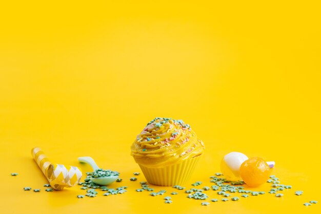 Ein gelber Kuchen der Vorderansicht köstlich und lecker zusammen mit grünen sternförmigen Bonbons auf gelbem Schreibtisch, süßer Zuckerfarbkuchen