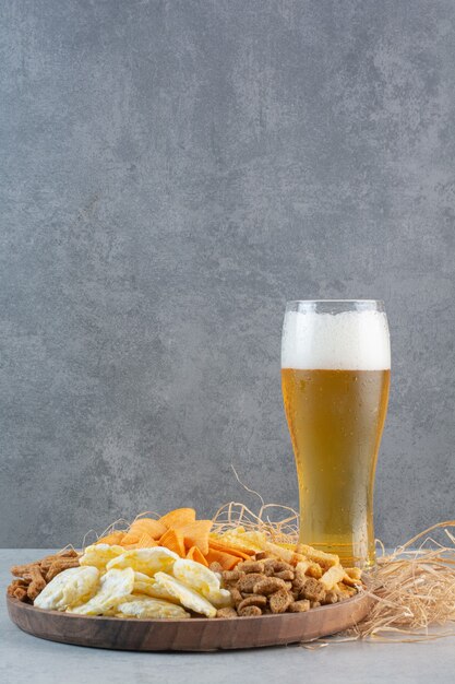 Ein Glas Bier mit Weizen und Kartoffelchips auf Heu.