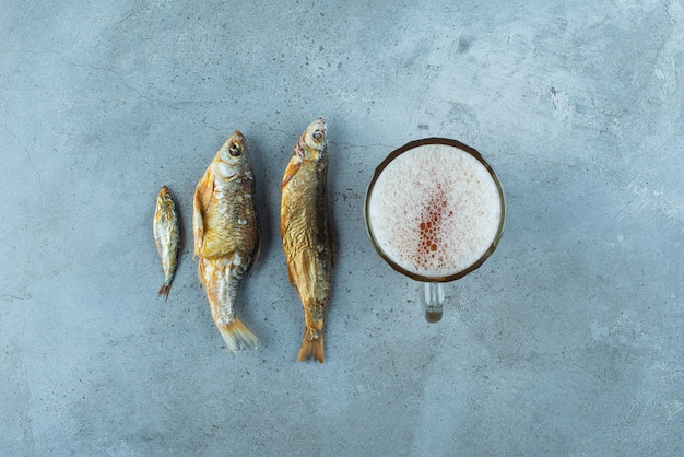 Kostenloses Foto ein glas bier neben fischen auf dem blauen tisch.