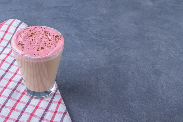 Ein Glas Cappuccino auf einem Geschirrtuch auf dem Marmorhintergrund. Foto in hoher Qualität