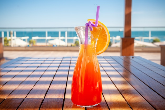 Ein Glas Fruchtsaft auf dem Boden mit Strand, Seitenansicht.