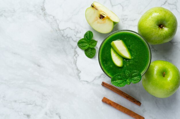 Ein Glas gesunder Smoothie aus grünem Apfel neben frische grüne Äpfel