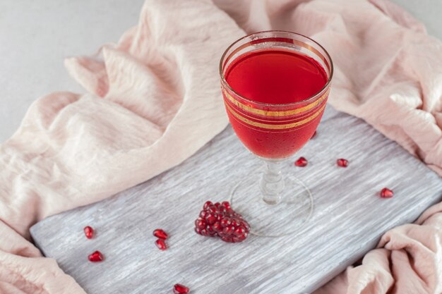 Ein Glas Granatapfelsaft mit frischen Samen auf Holzbrett