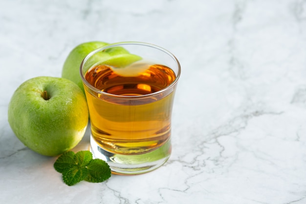 Ein glas grüner apfel-gesunder tee neben frischen grünen äpfeln