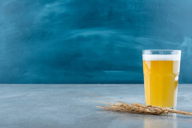 Ein Glas köstliches Bier und Weizen auf grauem Hintergrund. Foto in hoher Qualität