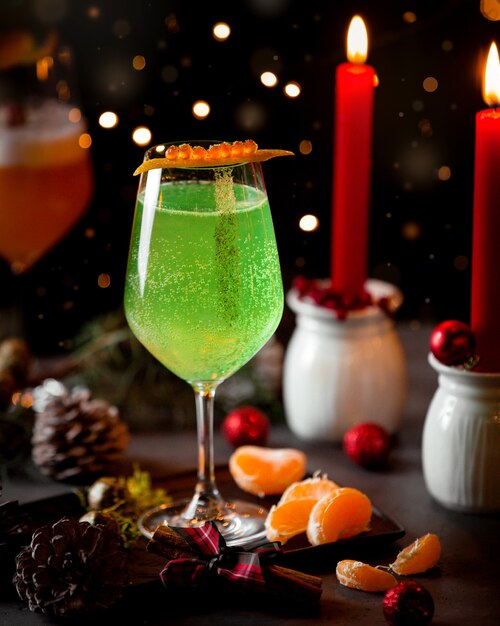 Ein Glas kohlensäurehaltiges grünes Getränk und Mandarine