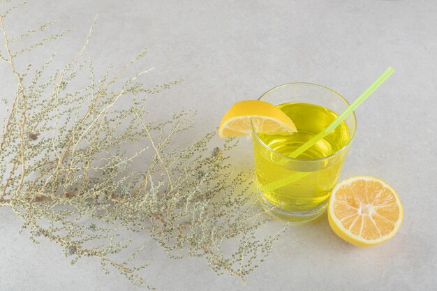 Ein Glas Limonade mit Zitrone und Stroh auf grauer Oberfläche