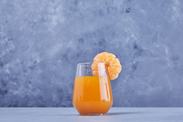Ein Glas Mandarinensaft mit Früchten.